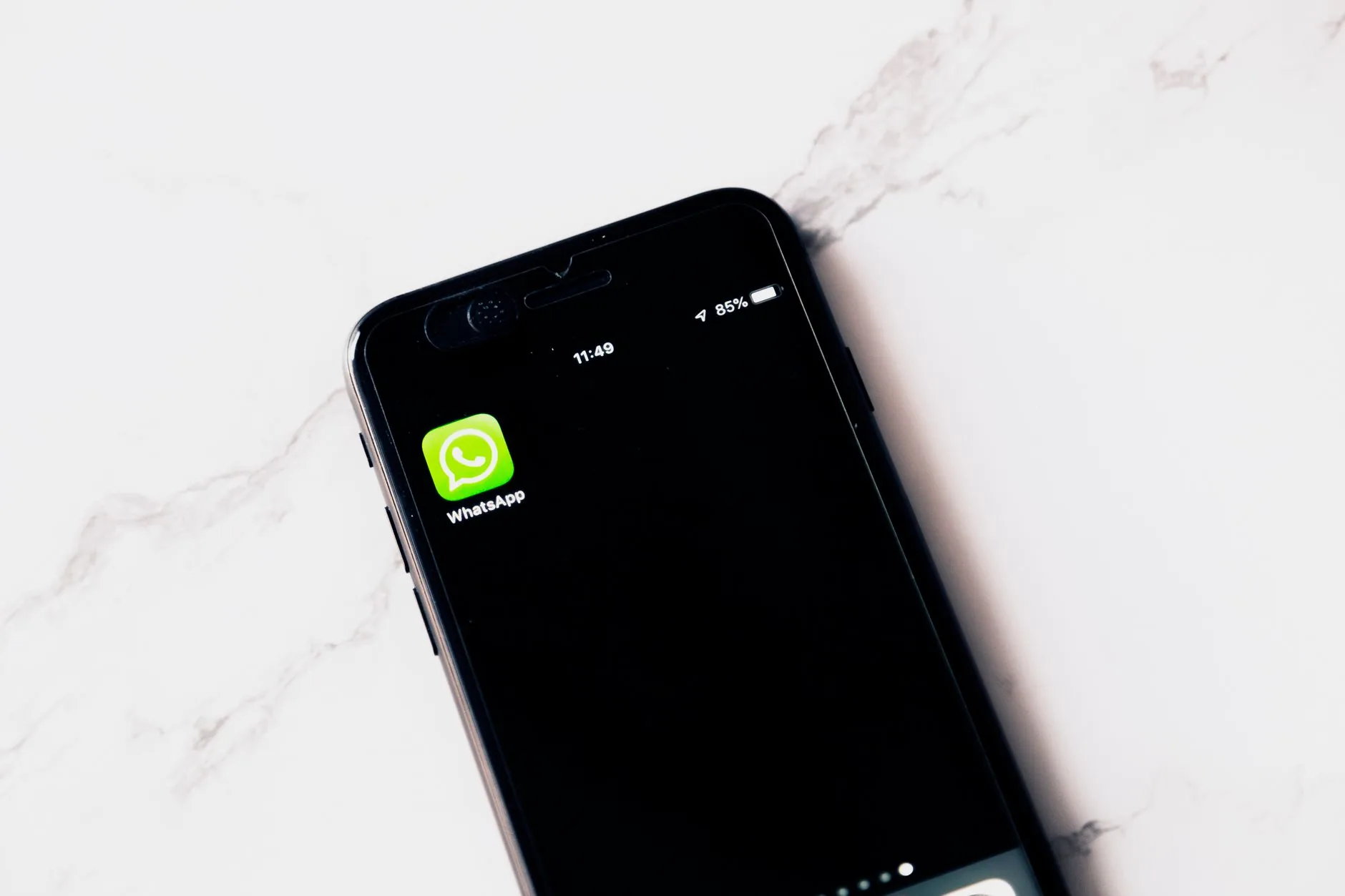 Telemóvel com uma conversa de atendimento no WhatsApp aberta ao lado de um caderno de notas