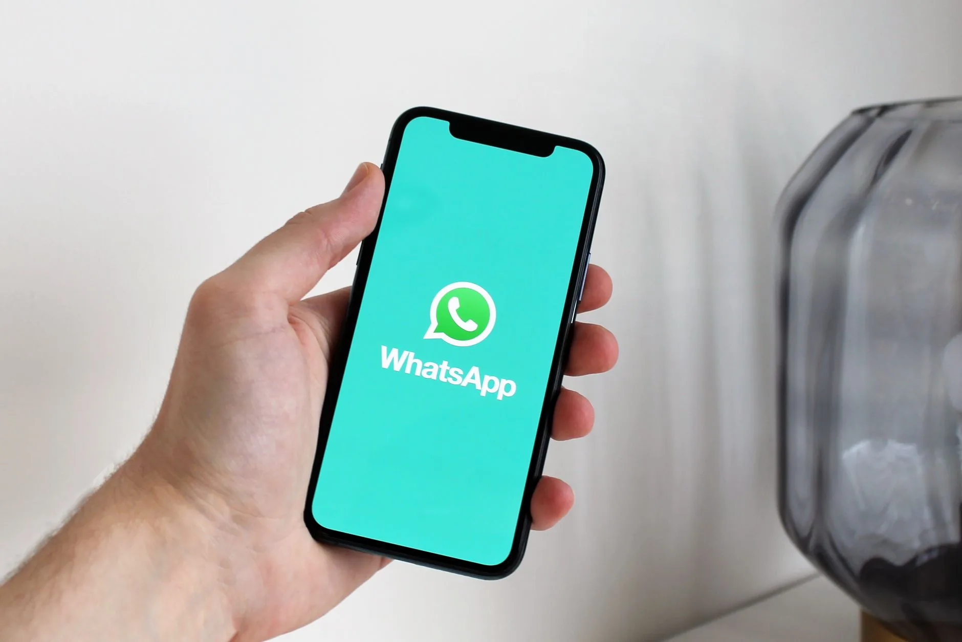 Telemóvel com conversa do WhatsApp Business aberta mostrando uma mensagem de saudação automática de uma empresa